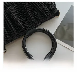 Detailed close-up of a black pleated tote bag with round handle and texture