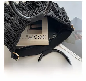 Detail view of large capacity black pleated tote bag with round handles and metal hardware