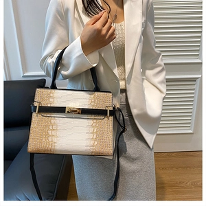 Detail of stone embossed pattern on a bicolor handbag with golden turn-lock closure