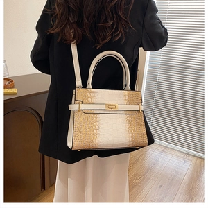 Detail view of large tote bag with crocodile texture and gold clasp on a model
