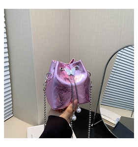 Detail der rosa Metallic-Beuteltasche mit Schmetterlingsschnalle und Perlen-Anhängern