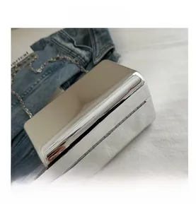 Detailed top view of a silver mirror acrylic box bag with chain strap on denim
