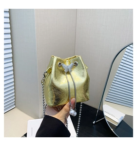 Nahaufnahme der goldenen Eimertasche mit Schmetterlingsschnalle und Perlenanhängern