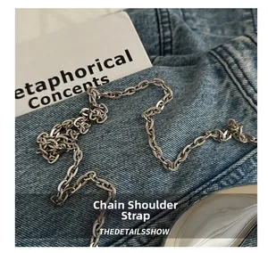 Close-up of polished silver metal chain strap on blue denim for acrylic evening bags