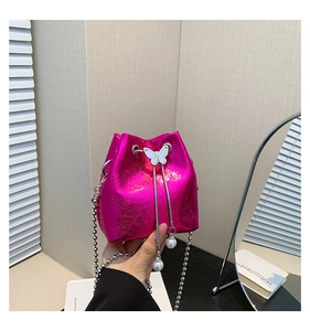 Details der fuchsiafarbenen Metallic-Beuteltasche mit Schmetterling und Perlenanhänger