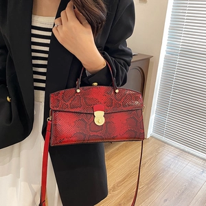 Red snakeskin embossed tote bag with gold metal lock handle shown in lifestyle setting