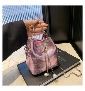 Detail einer metallisch rosa Beuteltasche mit Schmetterlingsverschluss und Perlen