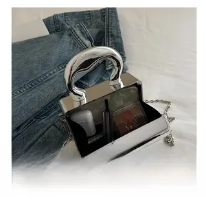 Detail showing the internal storage capacity of the silver metal box bag for makeup and tech