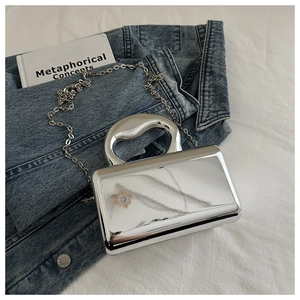 Detail of silver mirror acrylic box bag with stylish metallic handle on denim jacket