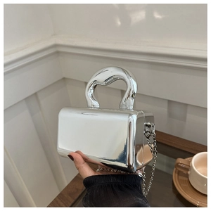 Close-up of silver mirror acrylic handbag with a sculptural handle and chain strap