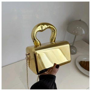 Close-up of metallic gold acrylic box bag with thick handle and sleek chain strap