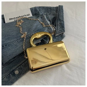 Close-up of golden mirror acrylic evening clutch bag on denim with chain strap