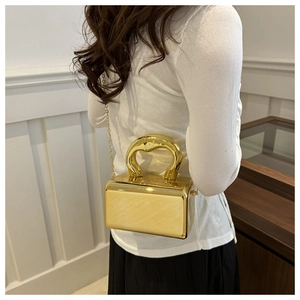 Chic gold metallic clutch bag with chunky handle and chain strap shown on a model