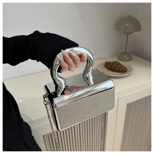 Detailed macro of a silver mirror acrylic clutch bag with metal ring handle and chain