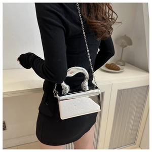 Silver mirror acrylic evening bag with a sleek metallic handle and chain strap on a model