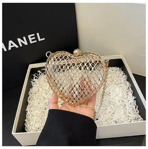Macro detail of golden heart-shaped hollow metal evening bag with polished ball clasp