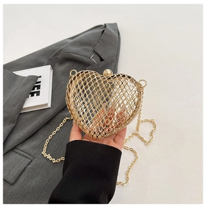 Detail of a heart-shaped gold hollow metal mesh evening bag with a luxury chain strap