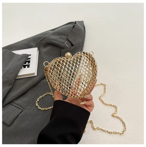 Detailed close-up of golden heart-shaped hollow metal clutch with intricate mesh texture