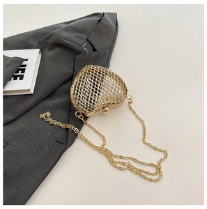 Detail of heart-shaped hollow metal mesh clutch bag with golden chain and ball clasp