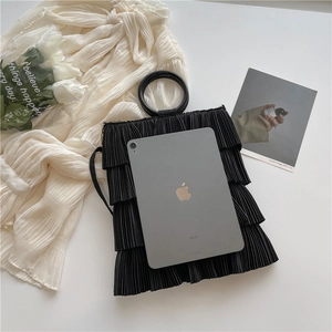 Chic black pleated bucket bag with circular handles shown with a tablet for size reference
