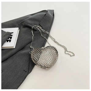 Detailed close-up of a silver heart-shaped hollow mesh evening bag with a metal chain strap