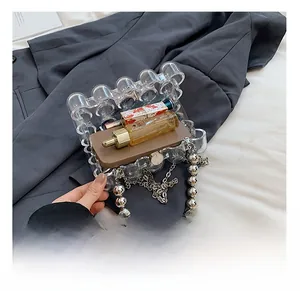 Macro view of transparent acrylic clutch with wavy edges and elegant silver beaded chain strap
