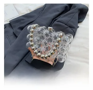 Detail showing transparent acrylic bubble clutch bag with silver chain strap and metal beads