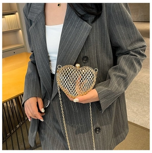Golden heart-shaped镂空metal clutch bag worn with gray striped blazer for fashion styling