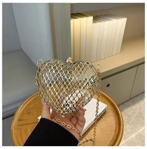 Close-up of heart-shaped hollow metal evening bag with gold mesh and chain strap