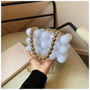 Close-up of white bubble texture hardshell handbag with gold beaded handle and metal chain