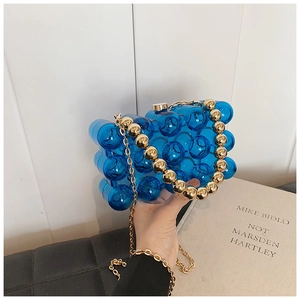 Dettaglio della borsa clutch in acrilico blu con manico a sfere e catena dorata