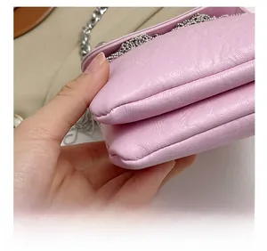 Detailed close-up of pink litchi grain leather crossbody bag with silver chain and stitching