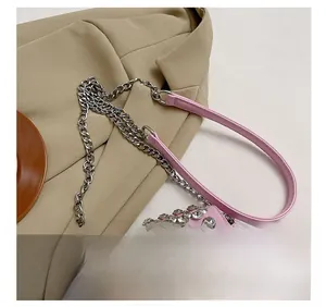 Detail showing pink faux leather bag with shiny rhinestones, tassels, and silver metal chain