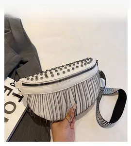 Detail of white leather chest bag featuring silver studs and long metal fringe tassels