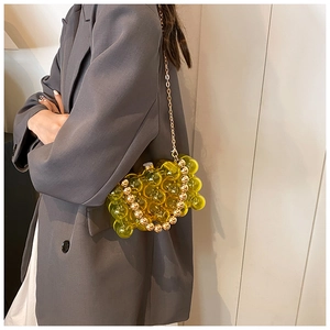 Detail of yellow acrylic bead bag with gold metal handle and chain strap on a blazer