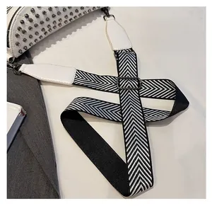 Detail of black and white herringbone woven strap with metal hooks and silver rivets