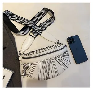 Detailed view of white tassel waist bag with silver studs and chevron woven strap