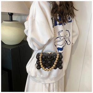Detail of black bubble texture handbag with gold beaded handle and chain strap
