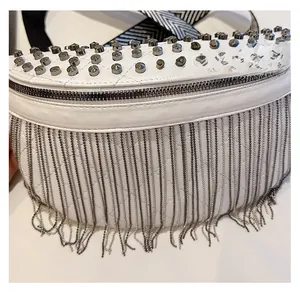 Detailed shot of white quilted leather waist bag with silver rivets and metal chain tassels
