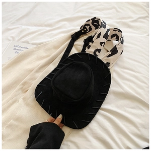 Detail of creative black cowboy hat backpack with cow print straps and suede texture