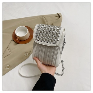 Close-up of white studded crossbody bag featuring silver rivet details and metallic fringes