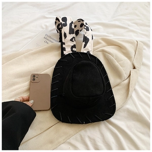 Detail of cowboy hat backpack with cow print straps on a stylish minimalist background