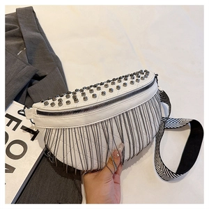 Detail of white quilted crossbody bag with silver studs, metal fringe, and wavy strap