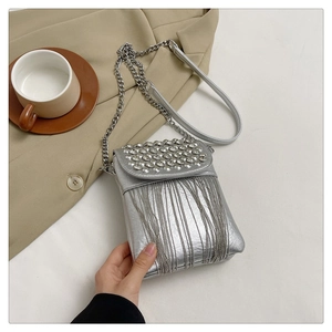 Close-up of silver mini crossbody bag with rhinestone studs and metallic tassel details