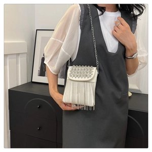Detail of white leather crossbody bag featuring sparkling rhinestones and silver chain tassels