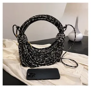 Detailed view of leopard print crescent bag with woven handle and smartphone for scale