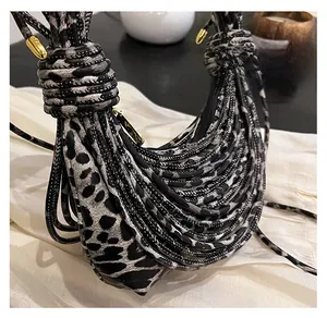 Detail of leopard print handbag showing woven knot handle and gold hardware accents