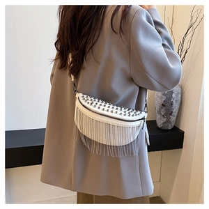 Detail view of white half-moon crossbody bag with silver rivet studs and long chain tassels