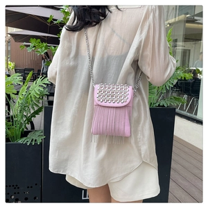 Detailed shot of pink leather crossbody bag with silver studs and metal fringe