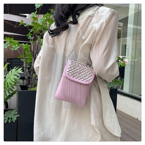 Close-up of pink crossbody bag with silver rhinestones and long metal chain tassels